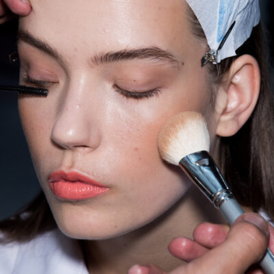 A close up of a woman blush skin tone as makeup is applied to her face