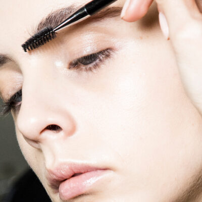 A close up of a woman applying brow gel to her eyebrows