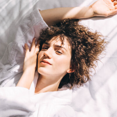 Woman in a white terry bathrobe on the bed in the morning