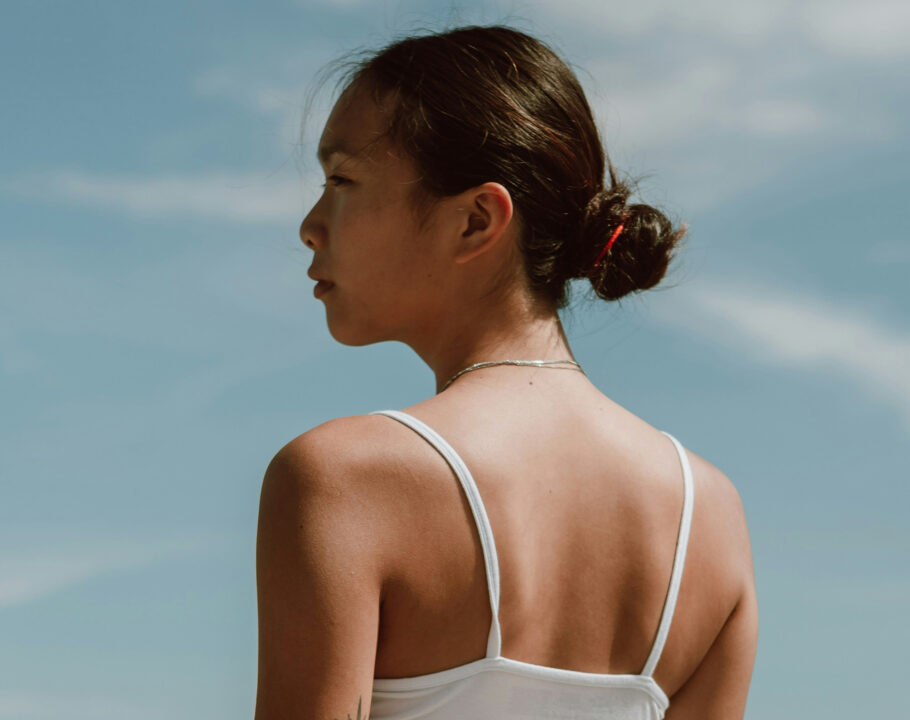 back view of Asian woman standing outdoors and looking away