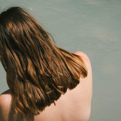 back view of woman with brown hair sitting on dock|honey brown hair|overtone chocolate brown coloring conditioner|MYDENTITY-myhero-nourishing-creme|