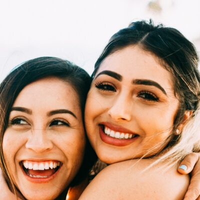dos mujeres latinas sonríen abrazándose