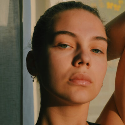 woman with arm up over her head in low sunlight|||