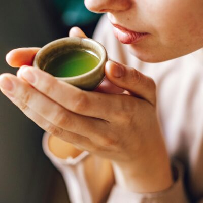 Close-up of a woman enjoying a hot matcha tea, highlighting a healthy lifestyle.
