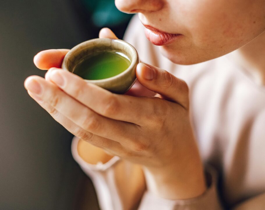 Close-up of a woman enjoying a hot matcha tea, highlighting a healthy lifestyle.