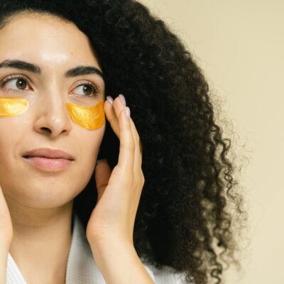 Close-up of a woman using gold under eye patches for skincare routine.