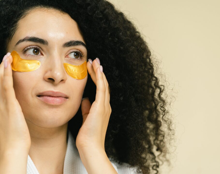 Close-up of a woman using gold under eye patches for skincare routine.
